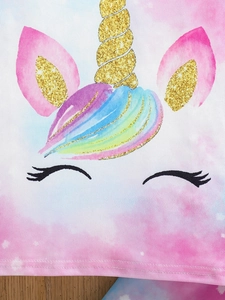 Close-up of glittery unicorn horn and rainbow mane on a pink tie-dye cotton fabric