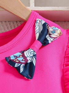 Detail of pink cotton knit top neckline with floral bow decoration and neat stitching