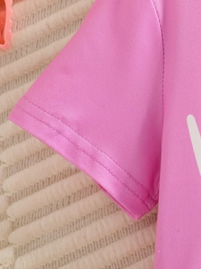 Gros plan sur la double couture du revers de la manche du t-shirt rose en coton