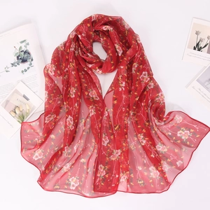 Detail view of lightweight red chiffon scarf with delicate floral prints on white background