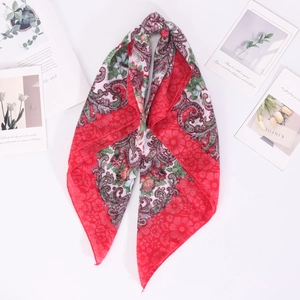 Détail d'un foulard carré rouge en coton et lin avec des motifs floraux paisley