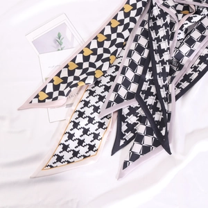 Foulards en soie avec motif pied-de-poule et damier posés sur un tissu blanc