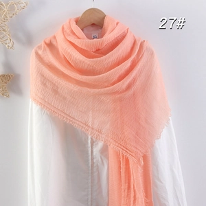 Détail d'une écharpe en coton lin corail avec texture froissée naturelle et bords effilochés