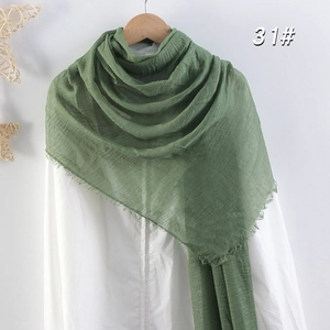 Détail d'une écharpe en coton et lin vert sauge avec franges et texture froissée