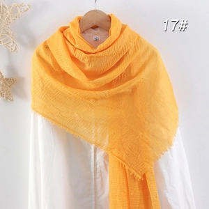 Écharpe en coton lin orange vif avec texture plissée et bords effilochés sur chemise blanche