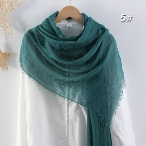 Détail d'une écharpe en coton et lin vert foncé montrant des franges et la texture