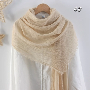 Détail d'une écharpe en coton et lin plissé beige clair avec bords à franges naturels