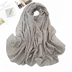 Detail of grey cotton linen scarf featuring gold leaf patterns and breathable texture