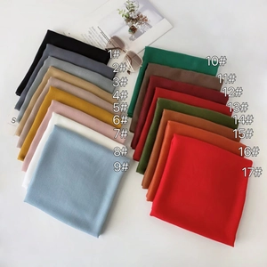 Flat lay of 17 colorful chiffon square scarves with numerical color codes and accessories