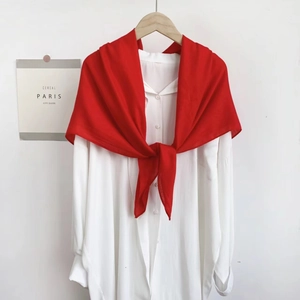 Detail of a bright red scarf knotted over a white collared shirt on a wooden hanger