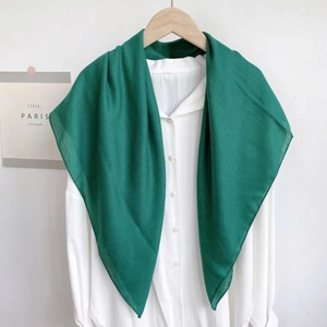 Close-up of lightweight dark green scarf draped over a white shirt on wooden hanger