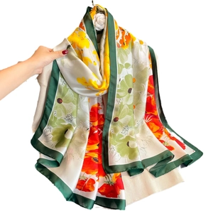 Elegant floral print satin silk scarf with emerald green border on white knitwear