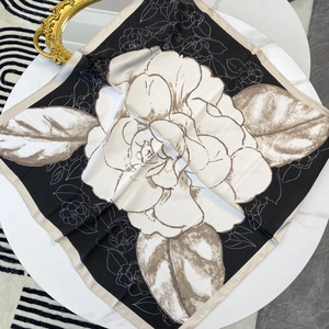 Elegant camellia print square silk scarf in black and white satin on a marble table