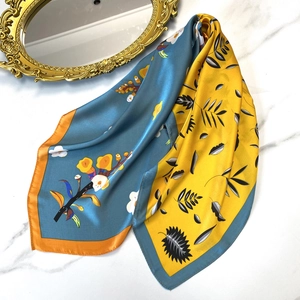Artistic floral square silk scarf in blue and yellow colors on marble background