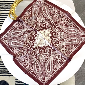 Carré de soie rouge vin de 70cm avec imprimé Paisley exposé sur une table blanche