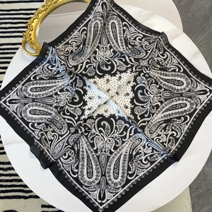 Carré de soie de 70 cm avec imprimé paisley noir et blanc classique sur une table