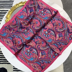 Fuchsia paisley satin silk scarf with vintage ethnic patterns on a white elegant table