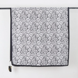 Elegant black and white rose floral print silk-feel scarf draped on a display rod