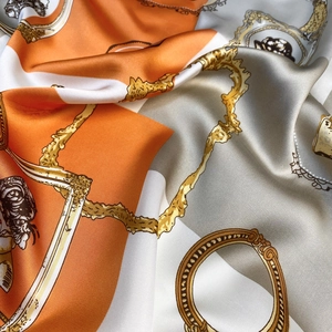 Détail d'un foulard en satin à motif baroque avec chaînes dorées et texture soyeuse