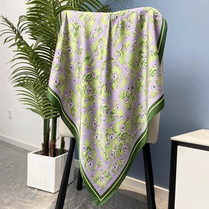 Square green and purple floral satin scarf draped on a white chair in a home setting