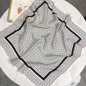 Carré en soie luxueux noir et or avec motif géométrique monogramme sur marbre blanc