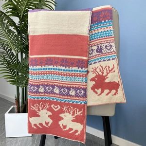 Détail d'une écharpe de Noël en maille avec motifs rennes et cœurs sur une chaise