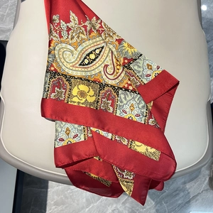 Détail d'un foulard en satin rouge avec motifs paisley et texture soyeuse brillante