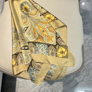 Détail d'un foulard en satin à motif paisley doré drapé sur une surface en cuir