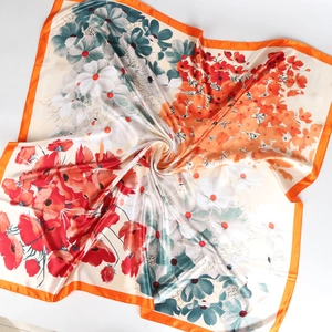 Détail de foulard carré en soie à fleurs avec bordure orange et texture satinée lisse
