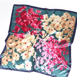 Détail du foulard en soie à motif floral sur fond vert foncé et fleurs vibrantes