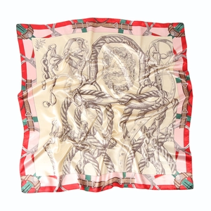 Detail of satin square scarf featuring golden horsebit print and elegant red border design