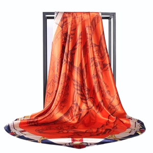 Detail of hanging satin scarf with equestrian chain print and orange silk texture