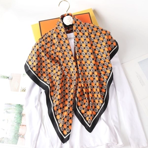 Detail eines Seidenschals mit orangefarbenem Blumenmuster und schwarzem Rand