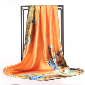 Orange satin silk scarf featuring traditional landscape painting hanging on a rack