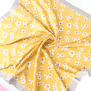 Detailed spiral fold of floral silk scarf with yellow petals and elegant grey borders