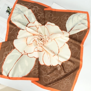 Detail of elegant silk satin square scarf with camellia print and orange edges