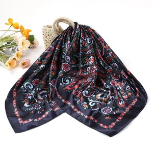 Detail of paisley pattern silk scarf with tassels draped on a woven straw handbag