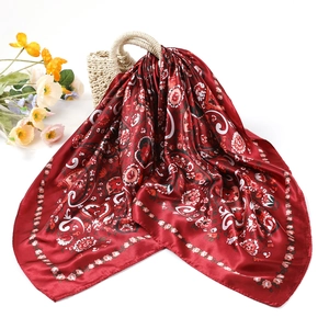 Macro detail of wine red square silk scarf featuring vintage floral and paisley patterns