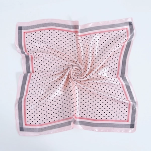 Detailed close-up of pink polka dot satin silk scarf showing soft fabric folds and texture