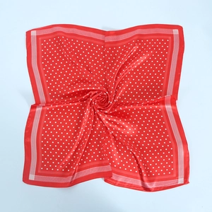 Detailed close-up of a red satin square scarf with white polka dots and silk texture