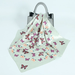 Hellgrünes Seidentuch mit Schmetterlingsdruck an einer grauen Designerhandtasche