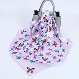 Detailansicht eines lavendelfarbenen Satin-Schals mit Schmetterlingsdruck auf einer Handtasche