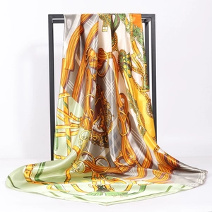Classic equestrian silk scarf with horse-bit print in orange and green on a metal hanger