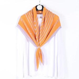 Orange pleated square scarf with gray stripes and chain print worn as a neckerchief