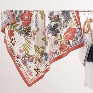 Detail of floral printed silk-like scarf with hibiscus and tropical leaf patterns