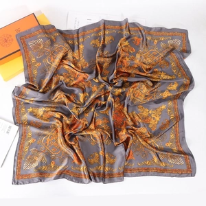 Détail macro du foulard en soie vintage avec des motifs de volutes dorées ornementées