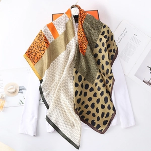 Large leopard print patchwork silk scarf displayed on a white top with elegant accessories