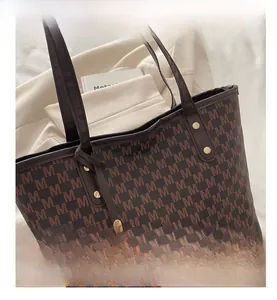 Close-up of the vintage M-pattern printed tote bag with metal rivets and a golden charm