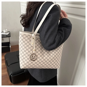 Detailed view of large monogram tote bag with gold M charm and elegant shoulder straps