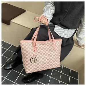Detail of printed large capacity tote bag with gold M metal charm and pink leather trim
